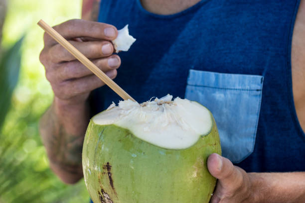 istock Man holding opened fresh coconut and eating coconut meat 1031581064