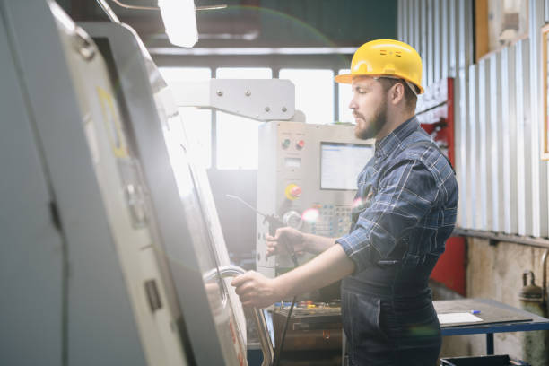 istock Serious confident handsome young bearded man in hardhat holding handle and opening machine door while working with cnc machine in workplace 1031581962