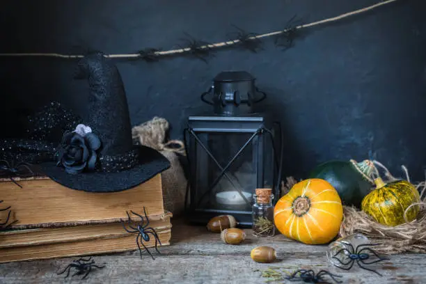 Halloween holiday background with pumpkin lantern spiders old books black witchhat toned