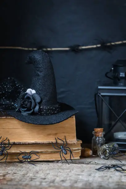 Halloween holiday background with lantern, spiders, old books, black witchhat, toned
