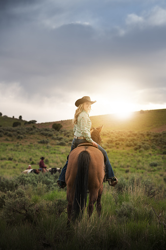 Cowgirl portrait, sunset, on horse, fields and Utah mountains
