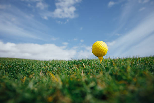istock yellow golf ball on tee, green grass and blue sky background 1031600684