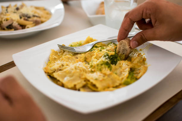 Close up of unrecognizable person eating pasta with cheese and vegetables with bread