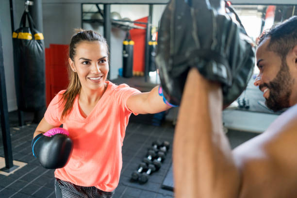 Latin american woman training kickboxing with her male coach Latin american woman training kickboxing with her male coach looking very happy kickboxing stock pictures, royalty-free photos & images