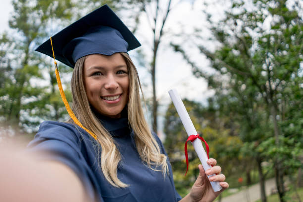 Beautiful college student taking a selfie on her graduation day looking at camera smiling very happy