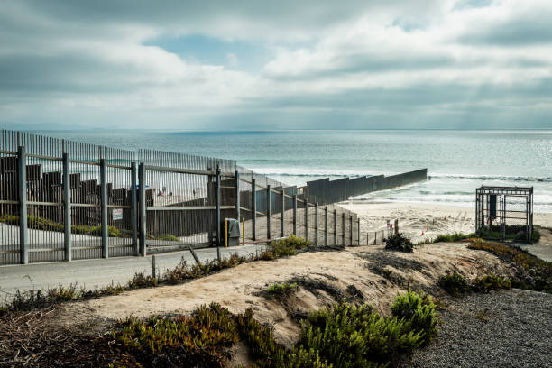 United States Border Wall with Mexico at the Pacific Ocean in California View from the California side of the US/Mexico border into Tijuana where the border fence meets the Pacific Ocean international border barrier stock pictures, royalty-free photos & images