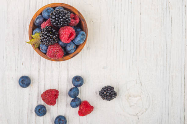 istock Blueberries and raspberries bowl on wooden table , top view 1031646686