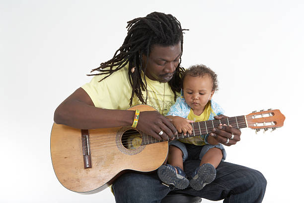 Father playing guitar to his baby son white background, white clothes, summer, studio, portrait, family father and son guitar stock pictures, royalty-free photos & images