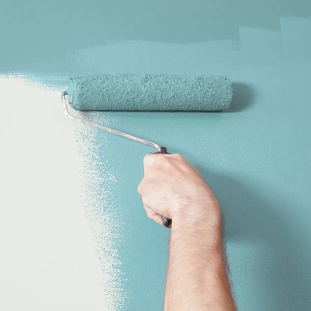 istock Person Painting a Wall Blue with a Paint Roller 1031660250
