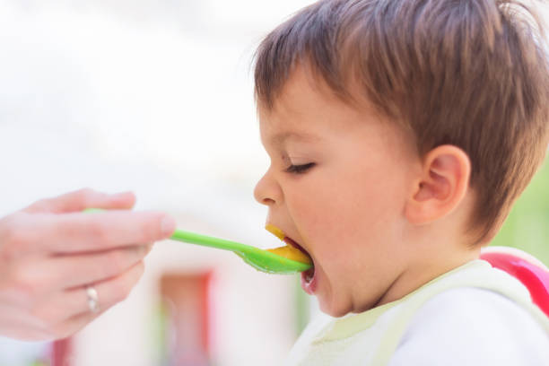 istock Baby eating the lunch while looking at the smartphone 1031663490