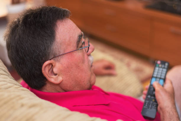 istock Back view of senior man watching tv holding remote control 1031663604