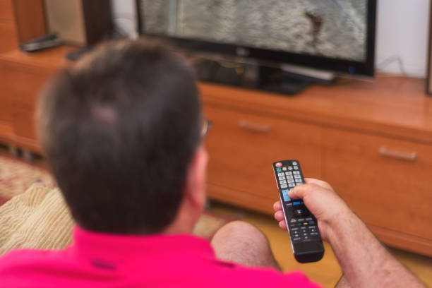 istock Back view of senior man watching tv holding remote control 1031663654
