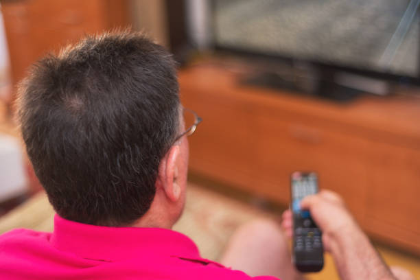istock Back view of senior man watching tv holding remote control 1031664028