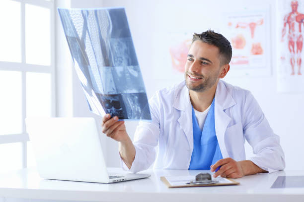 istock Young doctor sitting at his office desk and analyzing an x-ray 1031669014