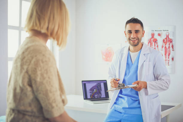 istock Handsome doctor is talking with young female patient and making notes while sitting in his office 1031669276