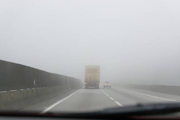 грузовик обго�няет автомобиль на двухполосной дороге с сильным туманом. - double lane стоковые фото и изображения