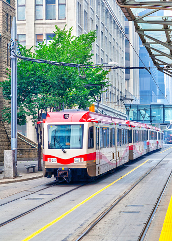 A modern Calgary transit train traveling on the streets of downtown Calgary. Vertical orientation.