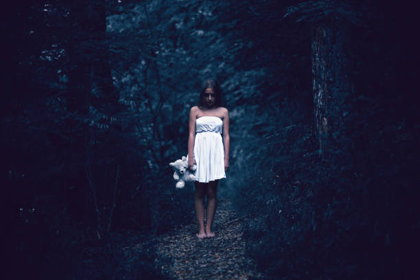 istock Creepy Girl with Teddy Bear Stand Alone in Dark Forest 1031698438