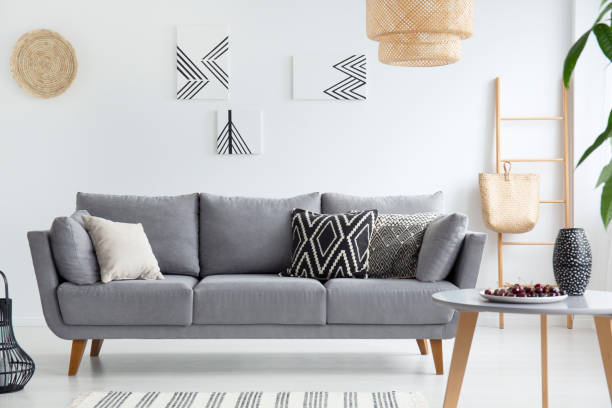 zoete smaak Klimatologische bergen Slepen Pillows On Grey Sofa In White Living Room Interior With Posters Lamp And  Wooden Table Real Photo Stock Photo - Download Image Now - iStock