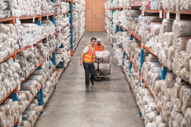 istock Two male workers in carpet factory pushing trolley 1031712382