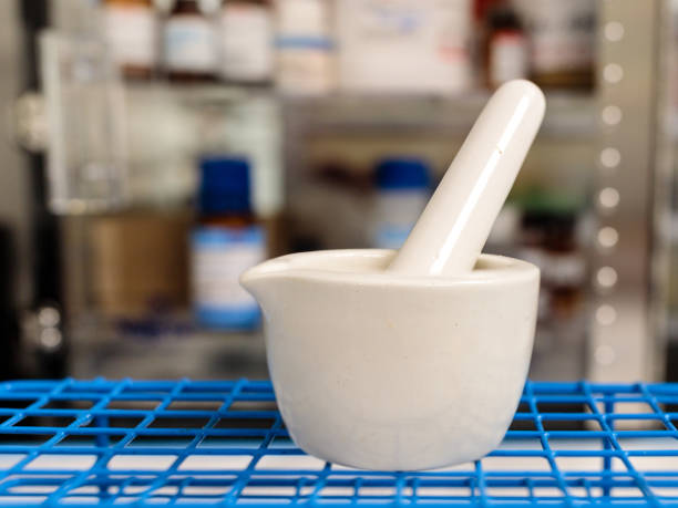 Mortar and pestle in a pharmacy A mortar and pestle in a pharmacy with medications in the background pharmaceutical compounding stock pictures, royalty-free photos & images