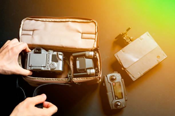 overhead top view of hand put camera accessories in bag on dark background