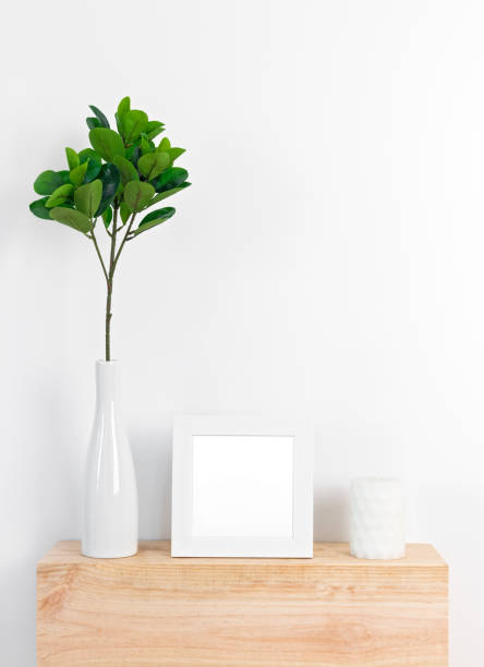 istock Stylish decor with white picture frame, ficus leaves and candle 1031725480