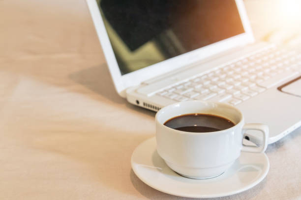 istock hot black coffee with steam in white cup on table with white laptop 1031727948