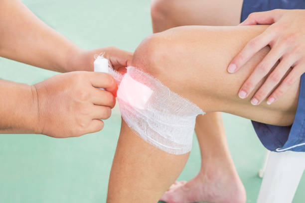 istock Nurse receiving first aid wounding bandage around knee 1031731382