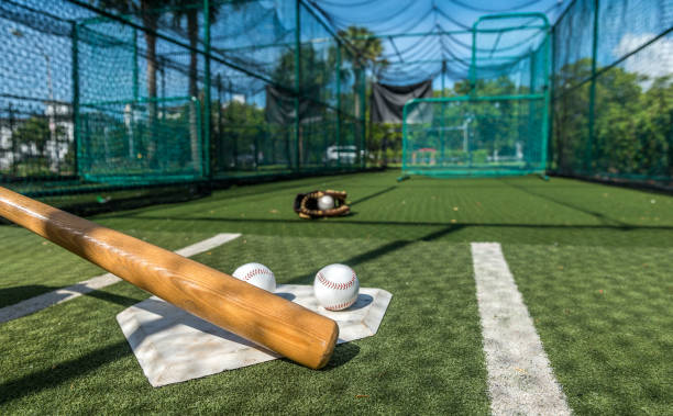 Hardball Hard training in the batting cage. baseball cage stock pictures, royalty-free photos & images