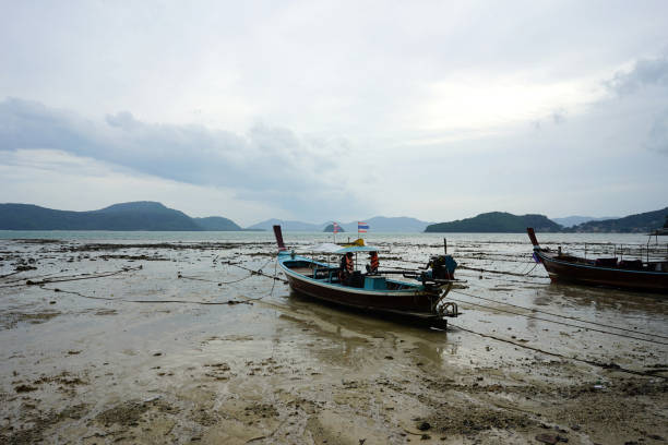 istock Fisherman boat parking on the lower tide beach with the dull sky background 1031767876