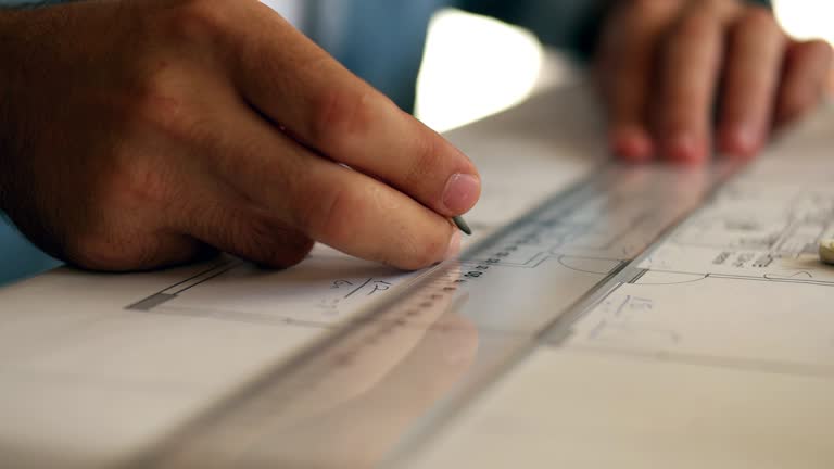 Architect man holding pencil working with laptop and blueprints for architectural plan, engineer sketching a construction project concept.