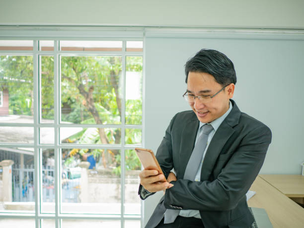 istock business man sitting on his disk and check his mobile phone 1031802224