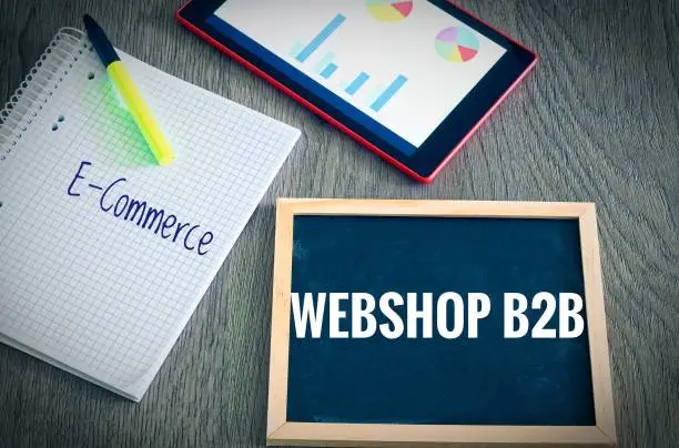 Plate with the inscription Webshop B2B (Business to Business) and E-Commerce  with a tablet Graphs and statistics and block to illustrate the increase in sales of an online shop