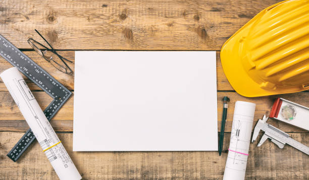 Architect workplace top view. White blank paper, project construction blueprints and engineering tools on wooden desk, copy space