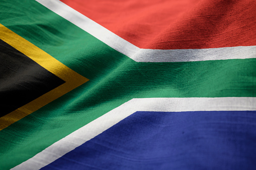 The national flag of South Africa with fabric texture waving in the wind on a blue sky. 3D Illustration