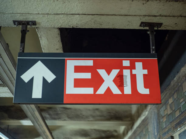 istock Red exit sign with arrow hanging in underground subway station 1031822144