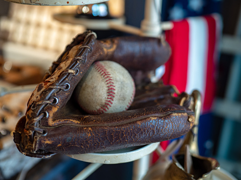 Baseball sitting in old fashioned glove with an American flag in background