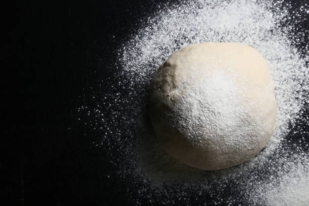 istock Raw dough with flour on black wooden table 1031826000