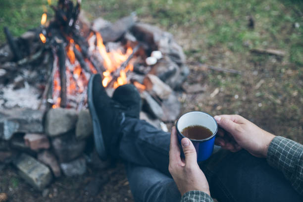 istock first point of view. man drinking tea in metal cup near camp fire 1031837518