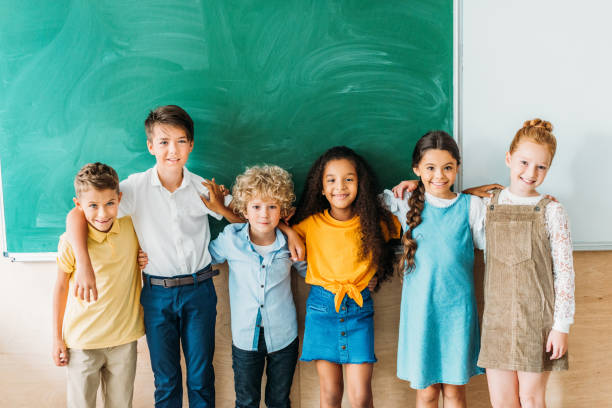 istock group of multiethnic schoolchildren embracing in front of blank chalkboard 1031844580