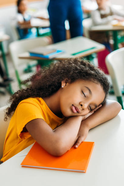 istock tired african american schoolgirl sleeping on desk during lesson 1031844598
