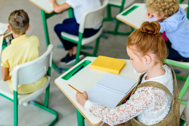 istock beautiful red haired schoolgirl writing in notebook during lesson 1031844614