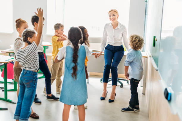 istock group of classmates standing around teacher at classroom and having fun 1031844730