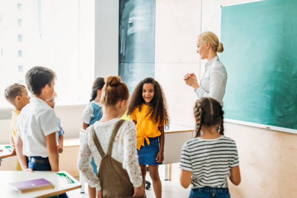 istock happy multiethnic classmates standing around teacher at classroom 1031844740
