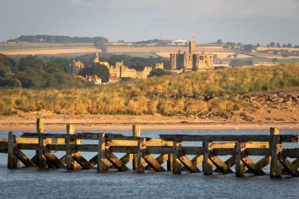 blick auf warkworth castle aus der ferne in den frühen morgenstunden. northumberland, vereinigtes königreich - warkworth castle stock-fotos und bilder