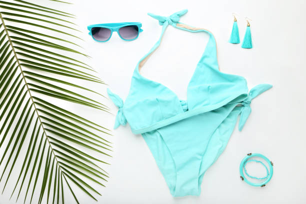 istock Blue swimsuit with green palm leaf and sunglasses on white background 1031849048