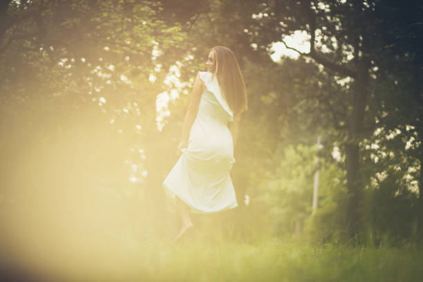 Young woman listening to music using headphones and dancing at park