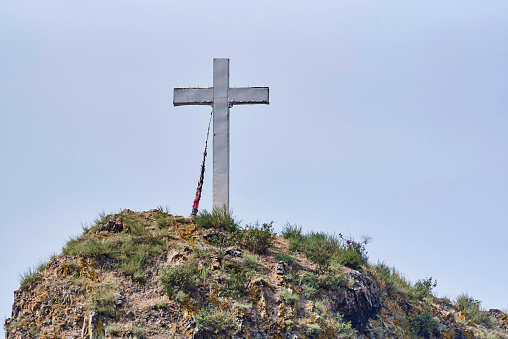 Cross on a rock against the background of a light sky.