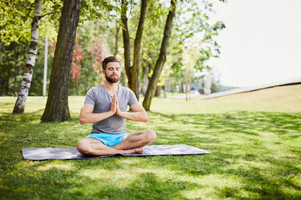 istock Focused young man meditating outdoors in a park 1031868090